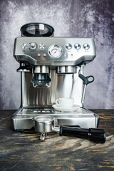 Modern espresso coffee machine with cup in kitchen on a dark wooden table.