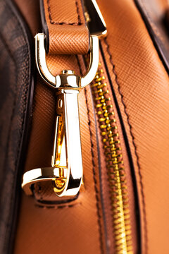 Metal gold-plated carabiner and ring-strap on a fashionable women's handbag. Accessory for a woman's look. Close-up.