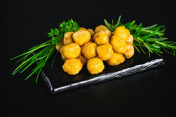 Breaded chicken nuggets. Semifinished chicken nuggets from chicken fillet on a dark background with fresh herbs. Quick cooking at home. Fast food. Breaded Chicken Inner Fillet.