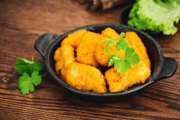 Breaded chicken nuggets. Semifinished chicken nuggets from chicken fillet on a dark background with fresh herbs. Quick cooking at home. Fast food. Breaded Chicken Inner Fillet.