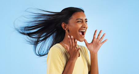 Woman, scream and wind for hair in studio for mock up on blue background with good news. Indian...