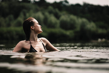 beautiful woman swims in the water of a lake river, swimming lessons.