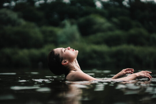 beautiful woman swims in the water of a lake river, swimming lessons.