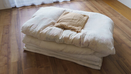 Fototapeta na wymiar フローリングの上に畳んだ布団と枕
