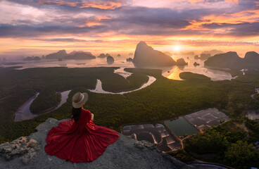 woman in red dress sitting looking to the sunrise Aerial view of Samet Nang Chee Viewpoint, Phang...