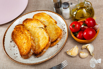 Ingredients for traditional Spanish appetizer Pa amb tomaquet, crispy toasted bread, fresh tomatoes, garlic on plates and decanter with olive oil, served on table