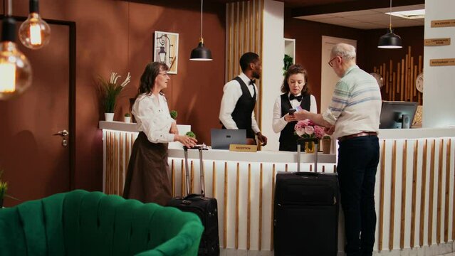 Senior Couple Paying For Room Reservation With Credit Card At Front Desk, Using Pos Transaction After Finishing Check In Process. Older Man Making Electronic Payment At All Inclusive Hotel.