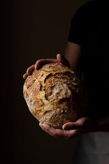 Attractive young Caucasian chef posing with white sourdough bread. The sourdough bread is the...