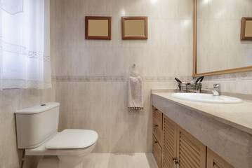 Bathroom tiled with cream-colored marble-like tiles, white porcelain sink on a cabinet with Venetian doors with a mirror built into the wall
