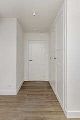 Entrance to a bedroom with large custom closet with white doors and wooden floors