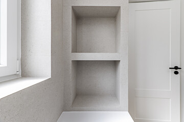 Bathroom with white bathtub with niche with two holes and a shelf and white access door