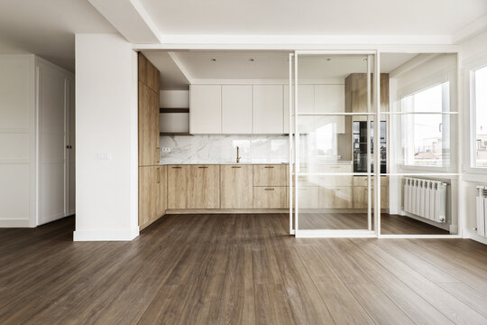 Front image Modern open kitchen with white metal and glass retractable screen with wooden flooring