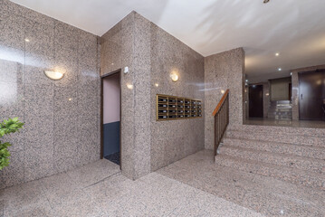 Hallway of a residential apartment building with pink polished granite walls and floors, steps of...