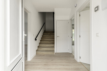 Hallway of a single-family home with stairs leading up to bedrooms and access doors to several rooms