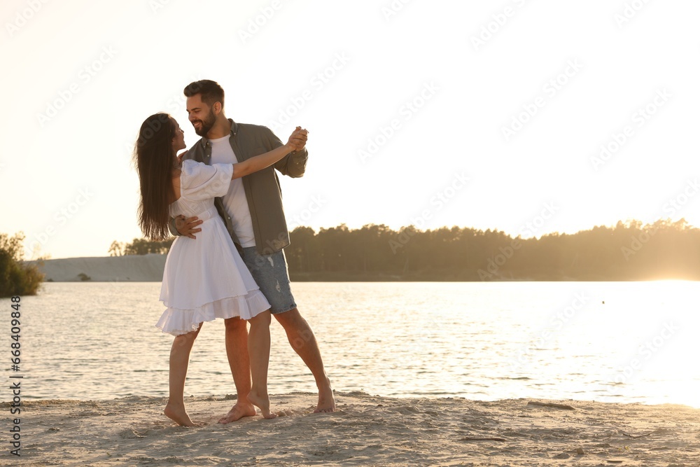 Wall mural happy couple dancing near river on sunny day. space for text