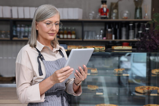Business owner using tablet in her cafe, space for text - Powered by Adobe