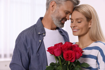 Happy affectionate couple with bouquet of roses at home. Romantic date