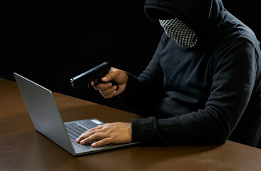 Hacker spy man one person in black hoodie sitting on a table looking computer laptop used login...