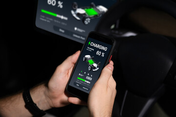 Electric car driver checks battery charging status, range and charging limit on app screen in the...