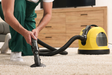 Dry cleaner's employee hoovering carpet with vacuum cleaner indoors, closeup