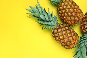 Whole ripe pineapples on yellow background, flat lay. Space for text