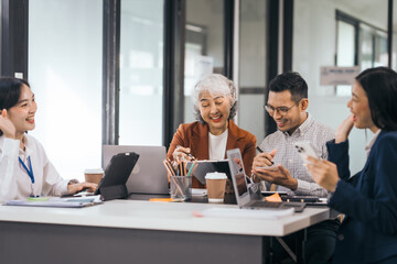 Four asian people in an office, working together on laptops, discussing tasks. annual gathering where attendees share and discuss opinions, presentation teamwork group meeting laptop in boardroom