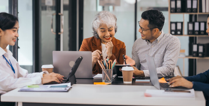 Four asian people in an office, working together on laptops, discussing tasks. annual gathering where attendees share and discuss opinions, presentation teamwork group meeting laptop in boardroom