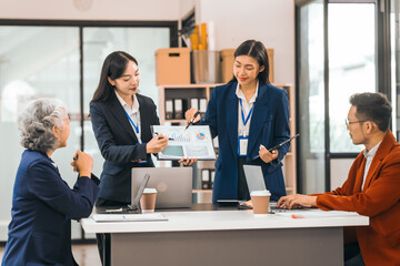 Four asian people in an office, working together on laptops, discussing tasks. annual gathering where attendees share and discuss opinions, presentation teamwork group meeting laptop in boardroom