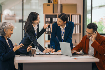 Four asian people in an office, working together on laptops, discussing tasks. annual gathering where attendees share and discuss opinions, presentation teamwork group meeting laptop in boardroom