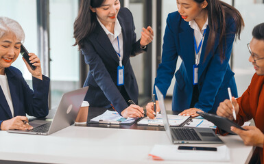 Four asian people in an office, working together on laptops, discussing tasks. annual gathering where attendees share and discuss opinions, presentation teamwork group meeting laptop in boardroom