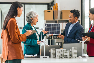 Obraz premium Group of asian business people meeting boardroom clean energy solutions. discussing solar panels, wind turbines, suggesting ideas for sustainable city. mature teaching, grey hair people, young adult