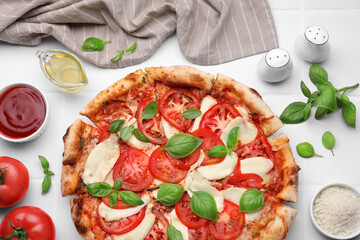 Delicious Caprese pizza and ingredients on white tiled table, flat lay