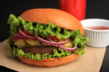 One tasty burger with vegetables, patty and lettuce on table, closeup