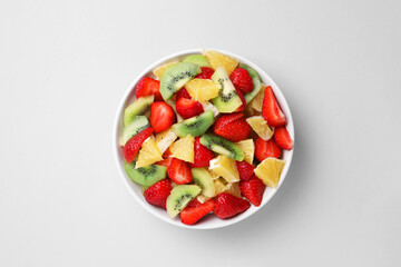 Yummy fruit salad in bowl on light grey background, top view