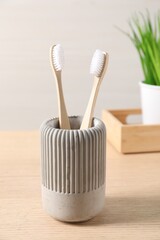 Fototapeta na wymiar Bamboo toothbrushes in holder on wooden table