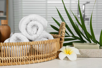 Beautiful composition with different spa products, flower and green leaves on white wooden table in bathroom, closeup