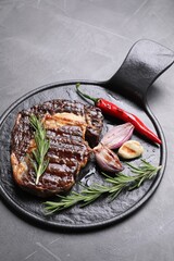 Delicious grilled beef meat, rosemary and spices on gray textured table, space for text