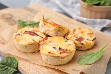 Naklejka na ściany i meble Delicious egg muffins with cheese and bacon on wooden board, closeup. Space for text