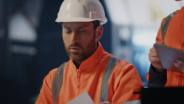 Two technicians discussing technical documentation working at factory close up.