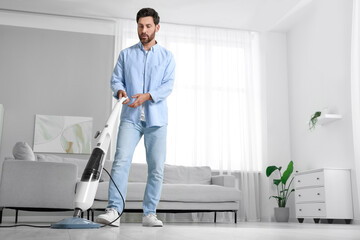 Man cleaning floor with steam mop at home. Space for text
