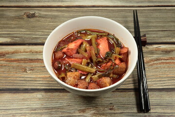 Traditional hot red sauce vegetarian soup mixed with fresh morning glory, plant ball and mushroom serving in the bowl. Famous vegan food in Chinese vegetarian festival.