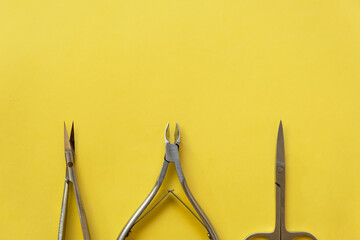 Professional manicure tools on yellow background. Manicure set. Top view. Cuticle pusher, cuticle...