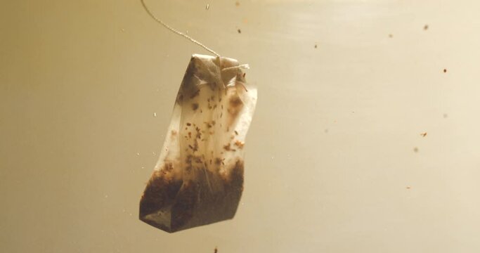 Tea bag plunging in water slow-motion, studio close up