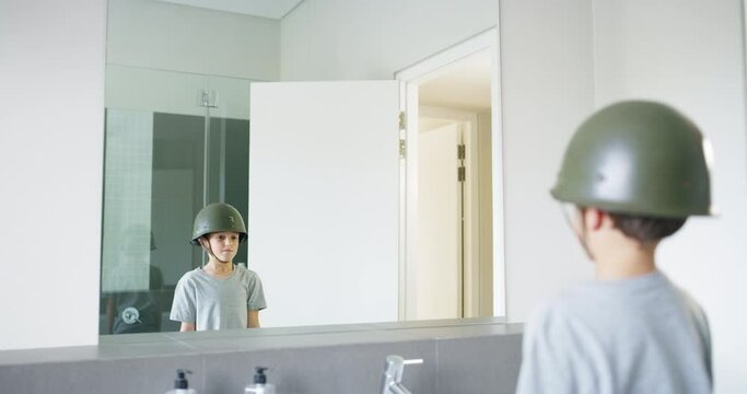 Pretend soldier, child with helmet in home and salute in mirror in bathroom with fantasy dress up play. Army hero, dream and imagine, boy thinking in restroom reflection with military games cosplay.