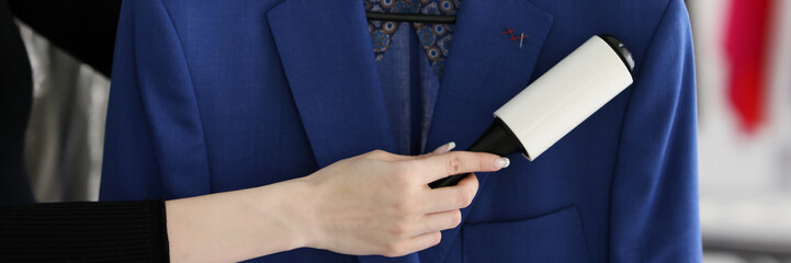 Woman removes pellets from blue woolen coat with roller