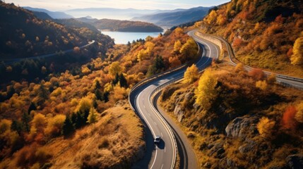 Aerial view over winding road on a mountain top with trees by autumn.