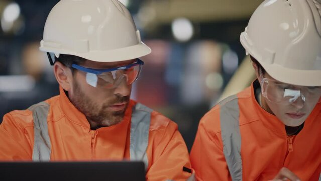 Serious professional engineers speaking together in protective helmets close up.