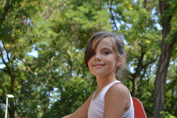 Fototapeta premium Cute kid girl 10 year old posing on nature background. Looking at camera
