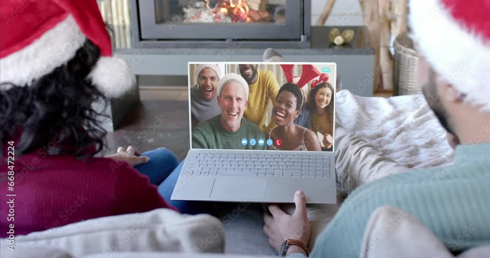 Wall mural Happy diverse couple and group of friends having christmas laptop video call, slow motion