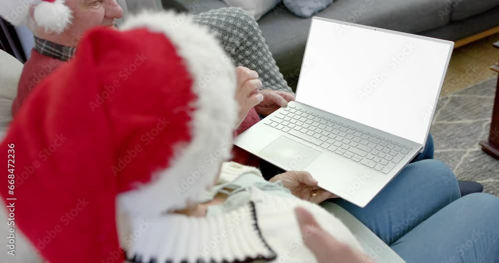 Wall mural Happy senior caucasian couple having christmas laptop video call with copy space, slow motion